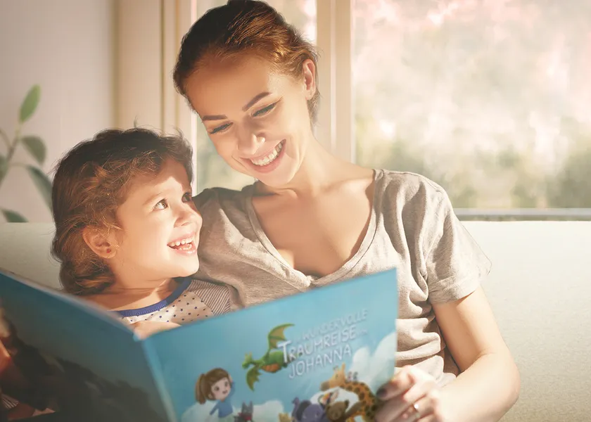 Frau liest ihrem Kind aus dem personalisierten Kinderbuch Die wundervolle Traumreise vor, sie sitzen dabei auf einem Sofa